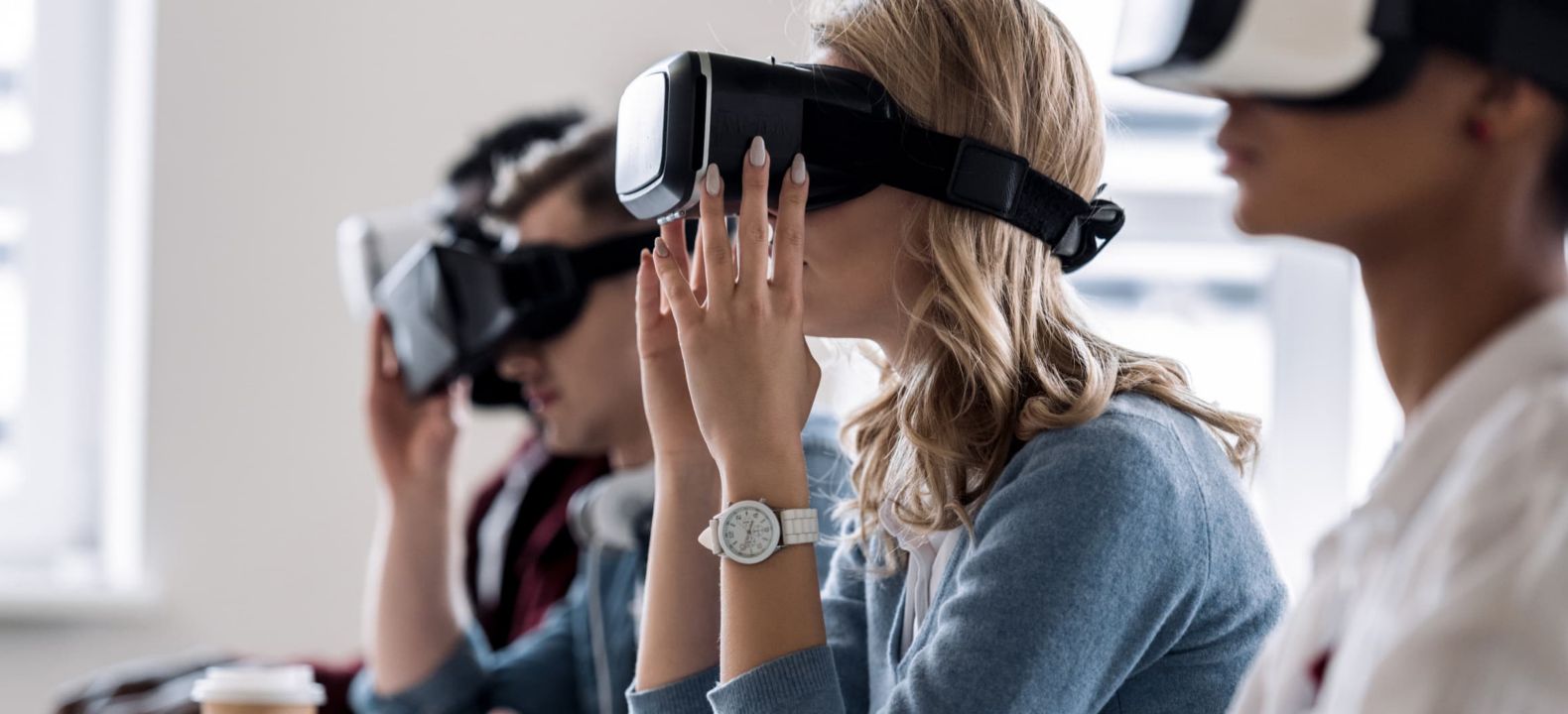 Estudiantes usando teclados y visores de VR para optimizar su aprendizaje en un aula.